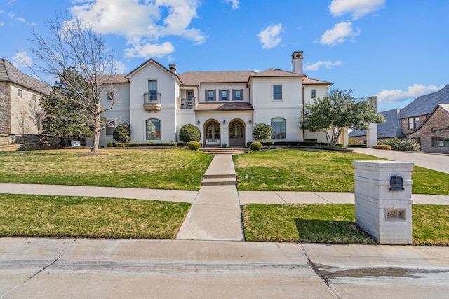 view of front of home with a front lawn, a chimney, and stucco siding