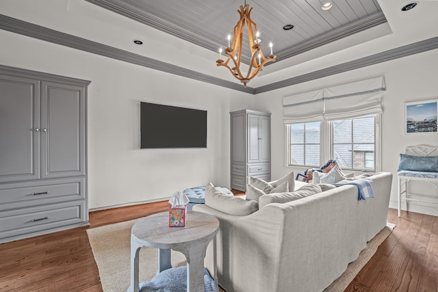 living area with a tray ceiling, dark wood-style flooring, crown molding, and an inviting chandelier