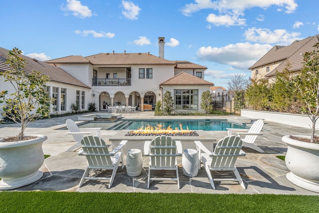 view of swimming pool featuring a patio, a fire pit, fence, and a pool with connected hot tub