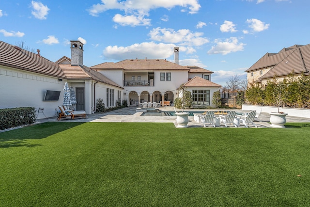 back of house with a balcony, an outdoor pool, a chimney, a yard, and a patio area