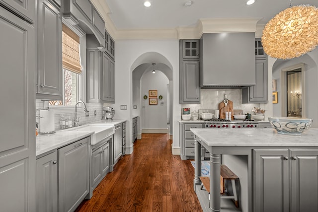 kitchen with gray cabinets, a sink, arched walkways, dark wood-style floors, and glass insert cabinets