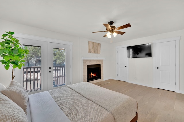 9231 Chimney Corner Ln, Dallas, TX 75243 - bedroom with access to outside, light wood finished floors, french doors, a warm lit fireplace, and a ceiling fan