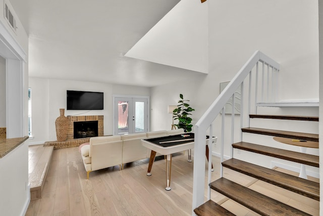 9231 Chimney Corner Ln, Dallas, TX 75243 - living room featuring a fireplace, light wood-style floors, visible vents, and stairs