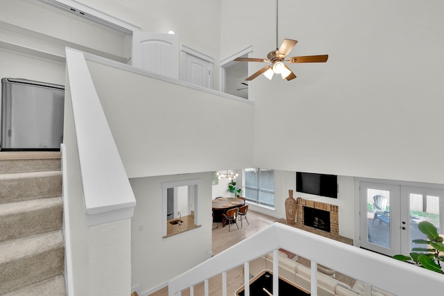 9231 Chimney Corner Ln, Dallas, TX 75243 - living room featuring a high ceiling, a ceiling fan, a fireplace, healthy amount of natural light, and french doors