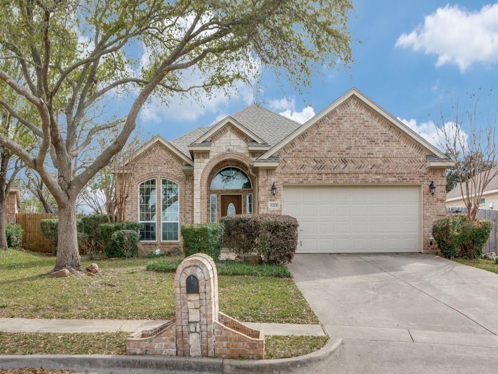 view of front of property featuring fence, an attached garage, concrete driveway, brick siding, and a front lawn