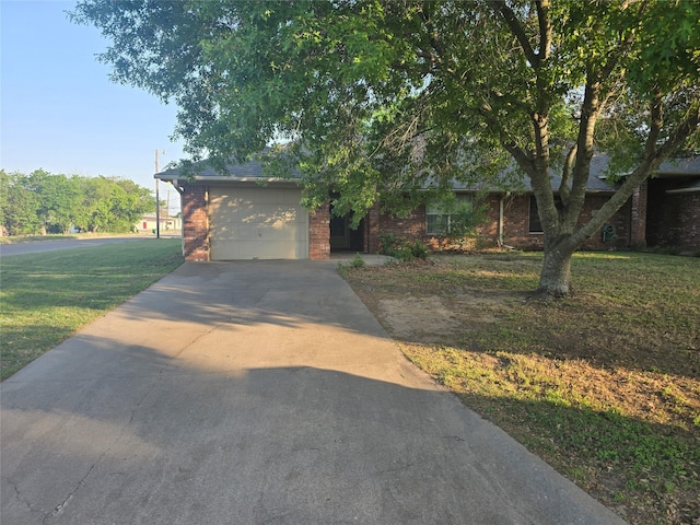 obstructed view of property featuring brick siding, driveway, a front yard, and a garage
