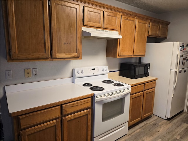 kitchen with light wood-type flooring, white appliances, brown cabinets, light countertops, and under cabinet range hood