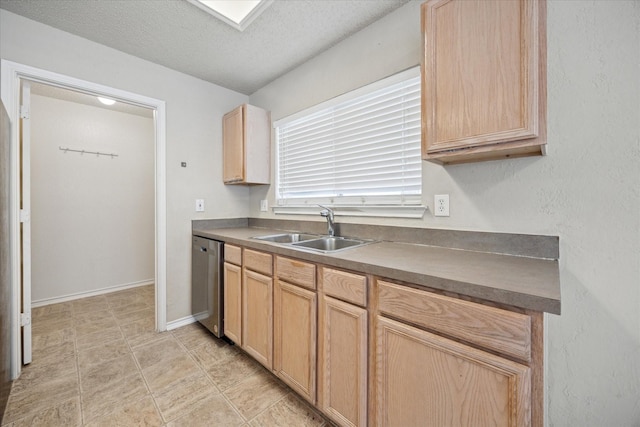 kitchen featuring a sink, stainless steel dishwasher, light brown cabinetry, baseboards, and a textured ceiling