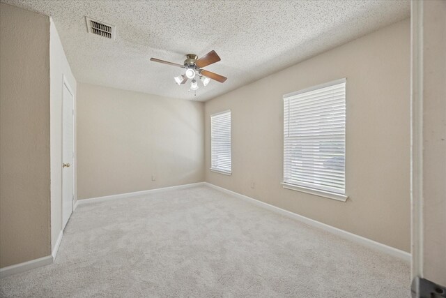 carpeted spare room with ceiling fan, a textured ceiling, and baseboards