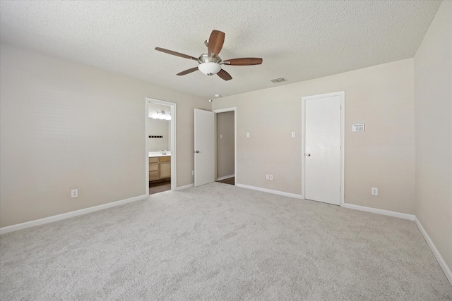 unfurnished bedroom with carpet floors, a ceiling fan, ensuite bathroom, a textured ceiling, and baseboards