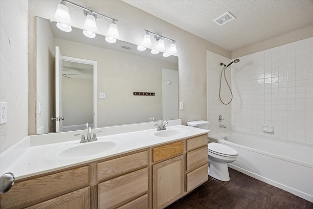 full bath featuring wood finished floors, a textured ceiling, toilet, shower / tub combination, and double vanity