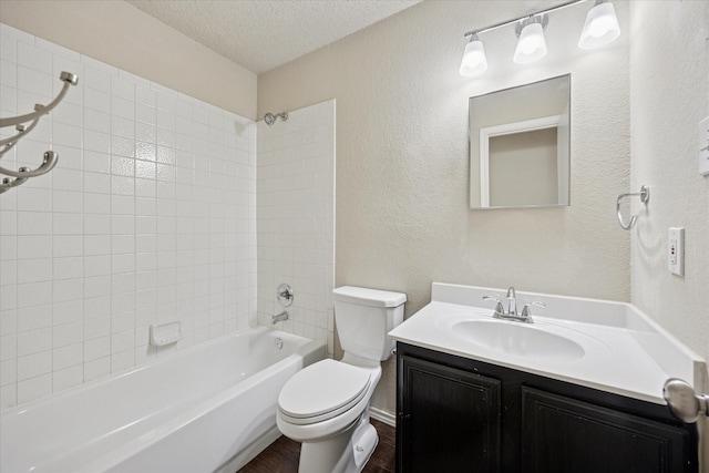 full bath with a textured ceiling, toilet, wood finished floors, vanity, and tub / shower combination