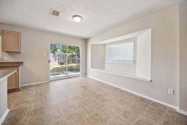 unfurnished dining area with a textured ceiling, baseboards, and a textured wall
