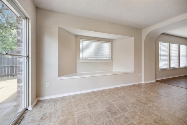 empty room featuring a textured ceiling and arched walkways