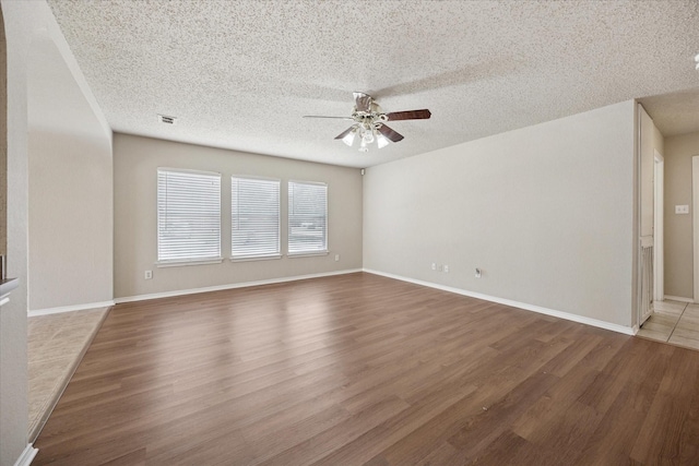 spare room with ceiling fan, wood finished floors, a textured ceiling, and baseboards