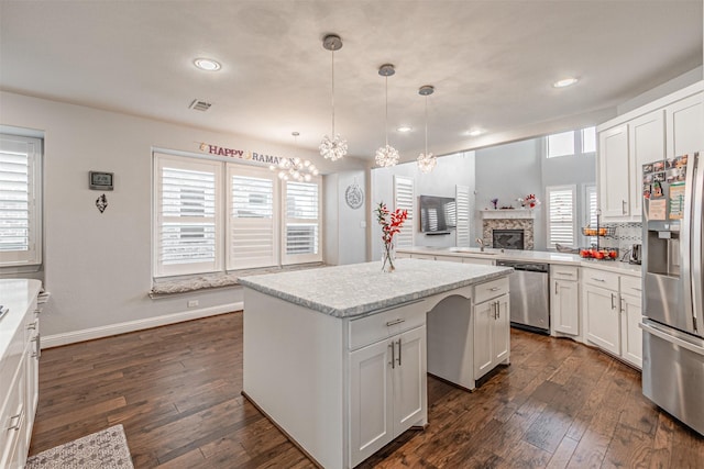 kitchen featuring a notable chandelier, stainless steel appliances, dark wood-style floors, and a center island