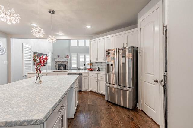 kitchen with dark wood-type flooring, a fireplace, stainless steel appliances, and an inviting chandelier