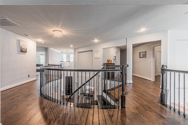 hallway featuring an upstairs landing, visible vents, and wood finished floors
