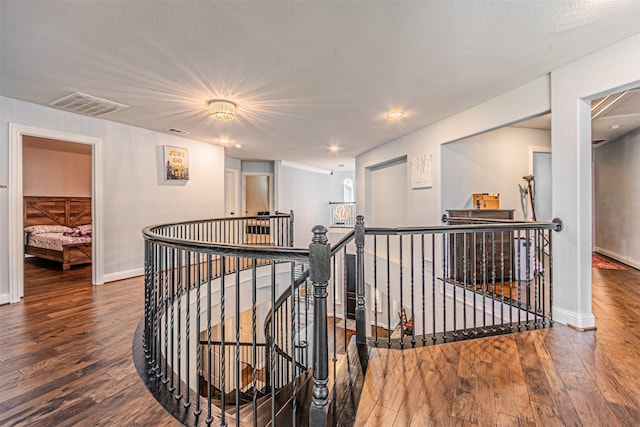 hall with an upstairs landing, visible vents, and hardwood / wood-style flooring