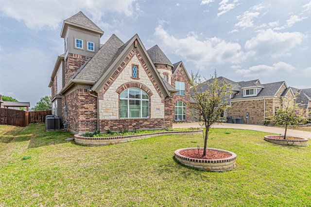 view of front of home with stone siding, central AC unit, fence, a front yard, and brick siding