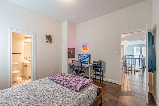 bedroom featuring baseboards, visible vents, wood finished floors, and ensuite bathroom
