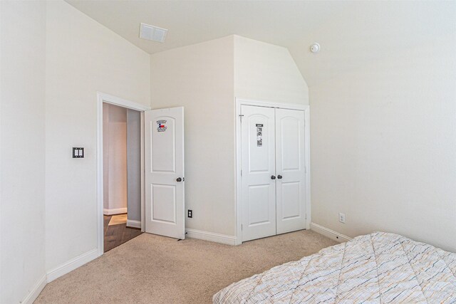 bedroom with a closet, carpet flooring, lofted ceiling, baseboards, and visible vents