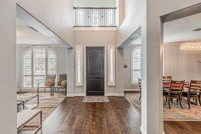 entrance foyer with hardwood / wood-style floors, baseboards, a notable chandelier, and plenty of natural light