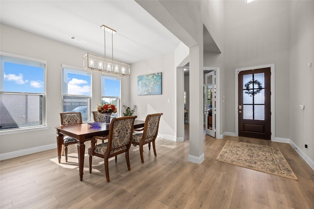 dining space featuring light wood-style flooring, an inviting chandelier, baseboards, and visible vents