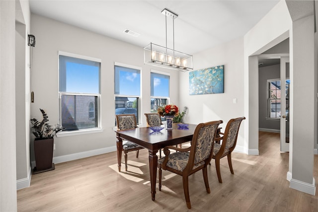 dining space featuring an inviting chandelier, light wood-style floors, baseboards, and visible vents