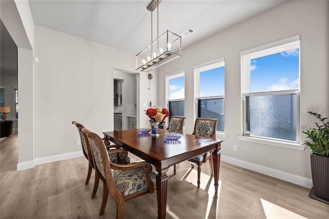dining space featuring visible vents, baseboards, a notable chandelier, and light wood-style floors