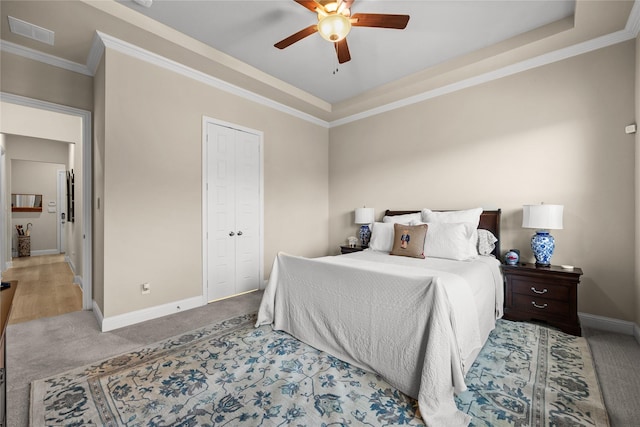 carpeted bedroom featuring a closet, a ceiling fan, ornamental molding, visible vents, and baseboards