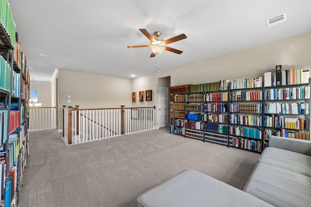 sitting room with carpet flooring, visible vents, an upstairs landing, and ceiling fan