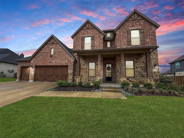 traditional-style home with a yard, a porch, stone siding, a garage, and concrete driveway