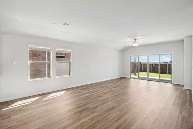 spare room featuring vaulted ceiling, a ceiling fan, wood finished floors, baseboards, and visible vents