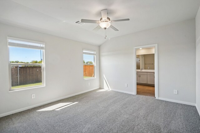 unfurnished bedroom with connected bathroom, vaulted ceiling, carpet flooring, baseboards, and visible vents