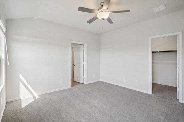 unfurnished bedroom with a closet, a walk in closet, baseboards, visible vents, and carpet