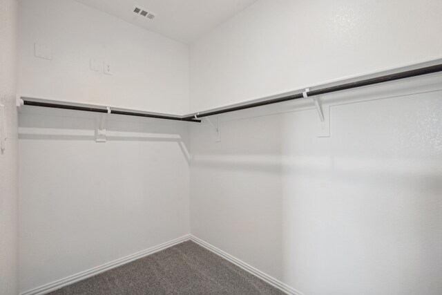 walk in closet with visible vents and dark colored carpet