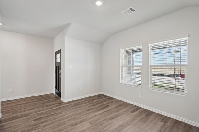 unfurnished room featuring visible vents, wood finished floors, and lofted ceiling