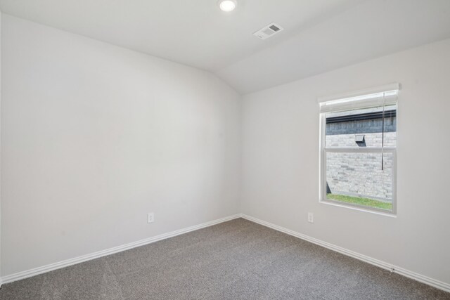 empty room with baseboards, lofted ceiling, visible vents, and carpet floors