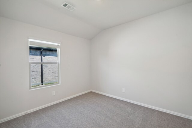 carpeted empty room with baseboards, visible vents, and vaulted ceiling