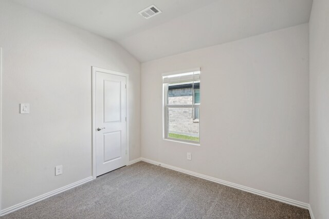 carpeted empty room featuring baseboards, lofted ceiling, and visible vents