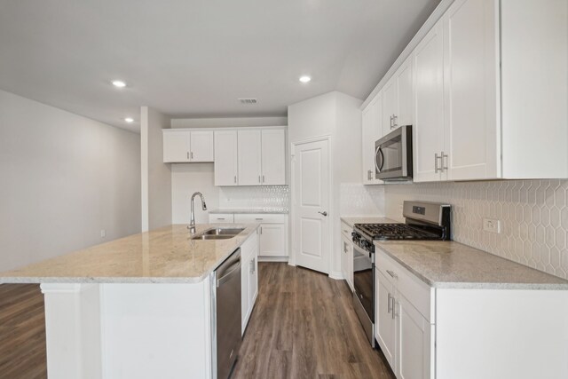 kitchen featuring dark wood finished floors, a sink, backsplash, and appliances with stainless steel finishes