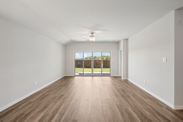 unfurnished room with baseboards, vaulted ceiling, wood finished floors, and a ceiling fan