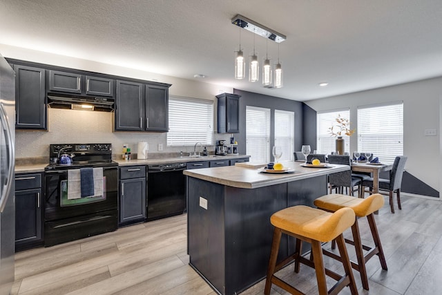 10617 Cochron Dr, Mckinney, TX 75072 - kitchen featuring light countertops, under cabinet range hood, black appliances, and a healthy amount of sunlight