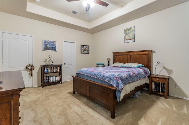 bedroom featuring a raised ceiling, light carpet, and baseboards