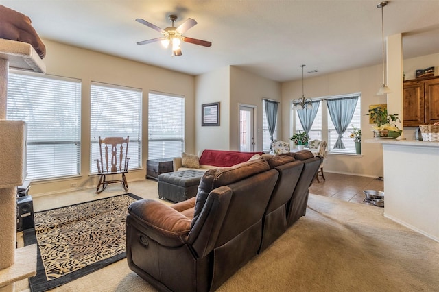 living room with light colored carpet, a healthy amount of sunlight, ceiling fan with notable chandelier, and baseboards