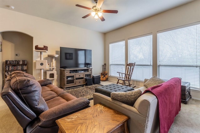 carpeted living area featuring arched walkways and ceiling fan
