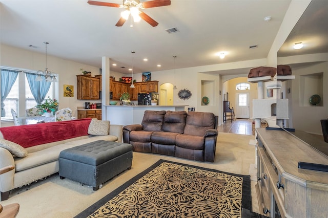 living room with arched walkways, visible vents, ceiling fan, and plenty of natural light