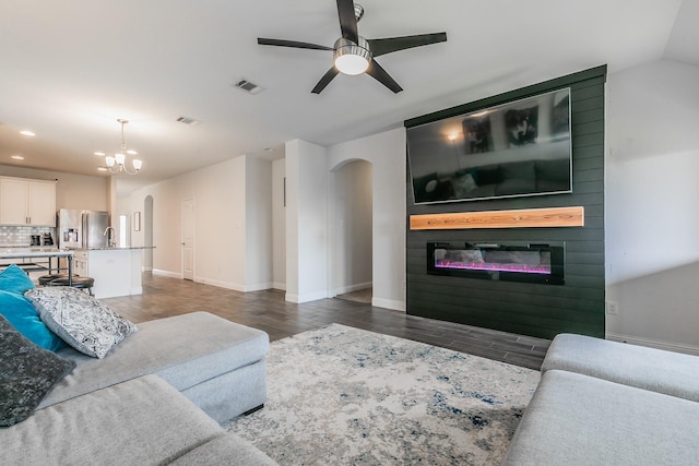 living area with wood finished floors, ceiling fan with notable chandelier, a glass covered fireplace, arched walkways, and recessed lighting