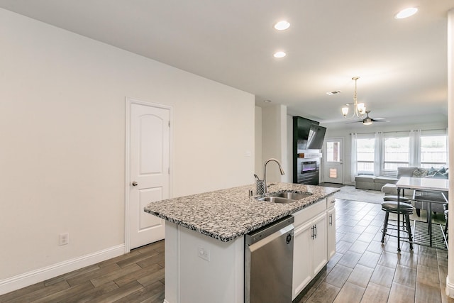 kitchen featuring dark wood finished floors, stainless steel dishwasher, a sink, a chandelier, and open floor plan